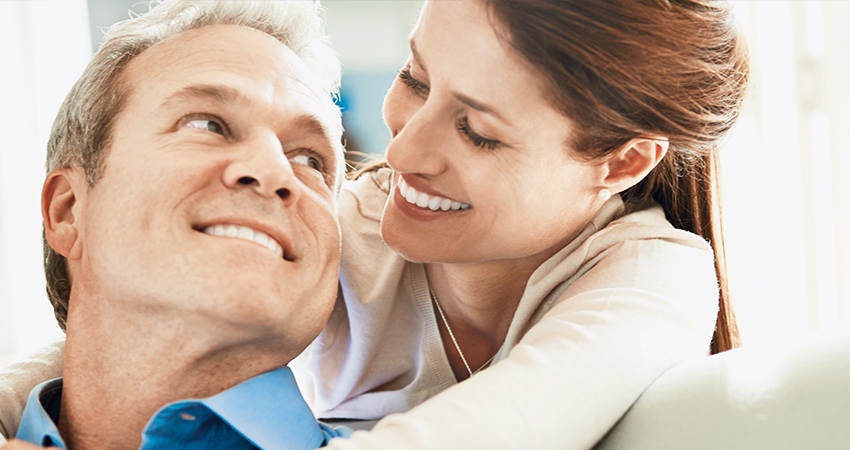 A wife smiles at her husband as their faces are close together