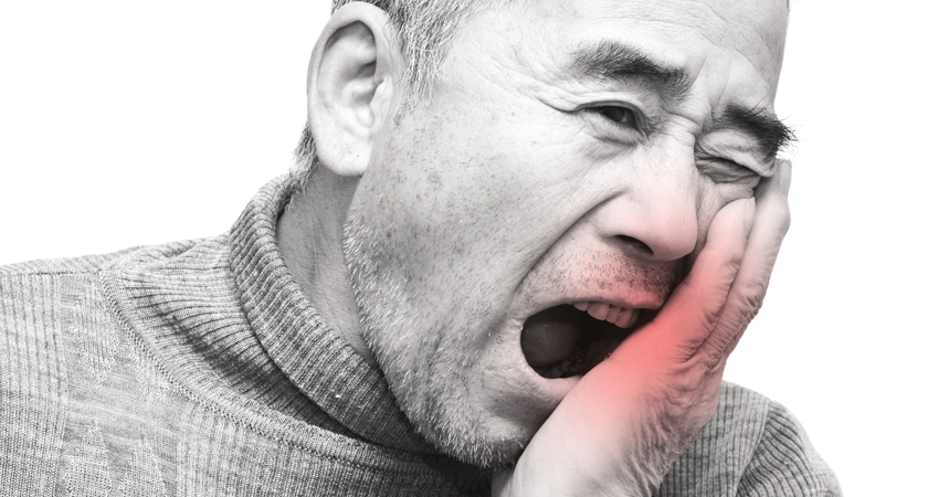 A man holds his mouth, appearing to endure pain