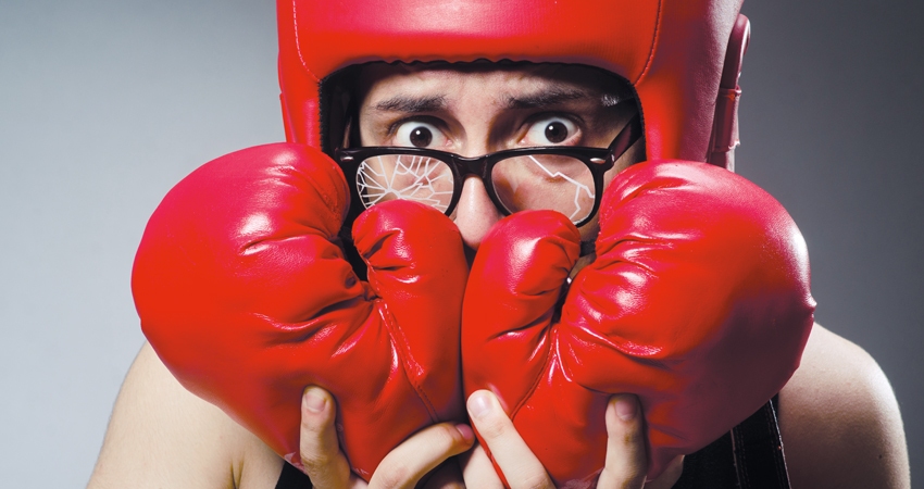 Boxer with broken glasses holds gloves up to face