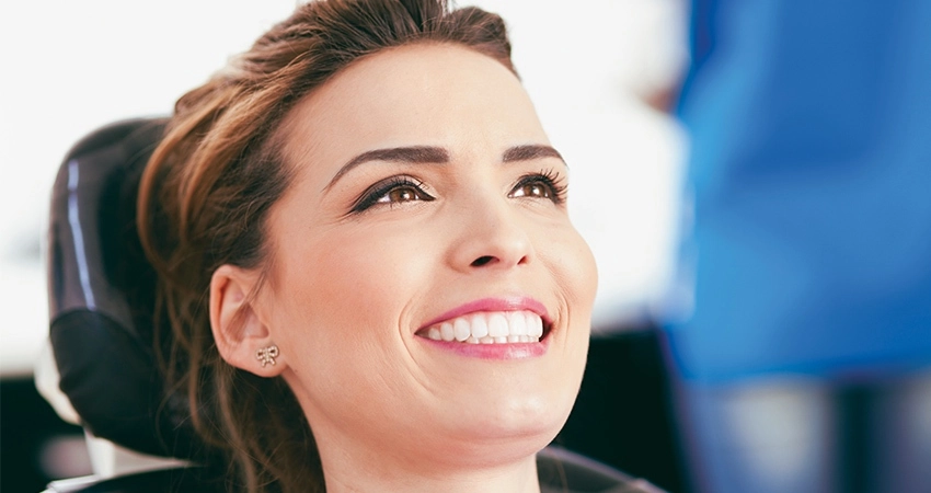 Woman leans back in dental chair and smiles